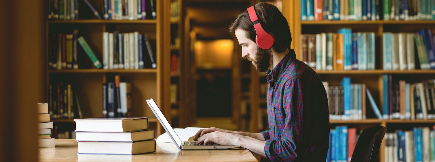 Understand your learning style - Man with headphones working on Laptop in library